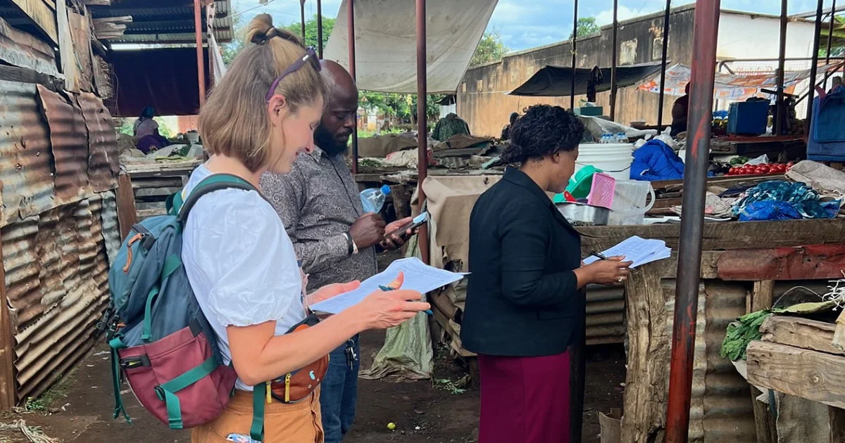 ublic health researchers conducting a survey or study in a local, open-air market, illustrating fieldwork and community engagement.