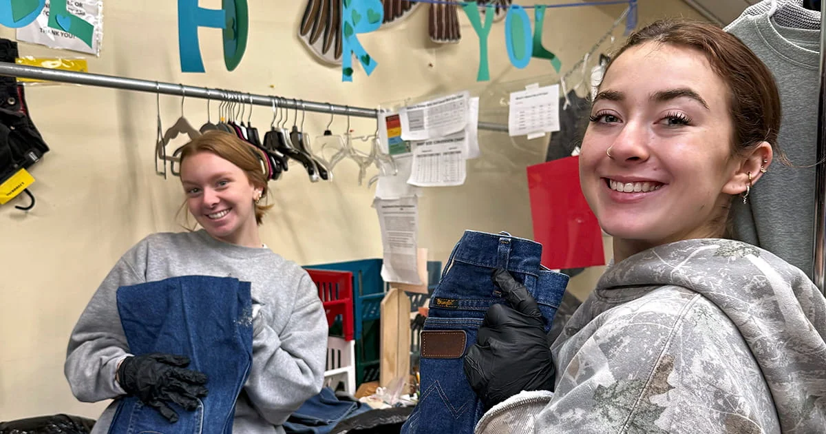 Student volunteers work at a donation drive or clothing distribution event, sorting and preparing donated jeans for distribution to the community.