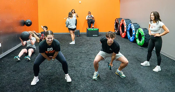 Students participate in a high-intensity functional fitness class, illustrating the importance of physical activity, campus recreation resources, and student wellness.