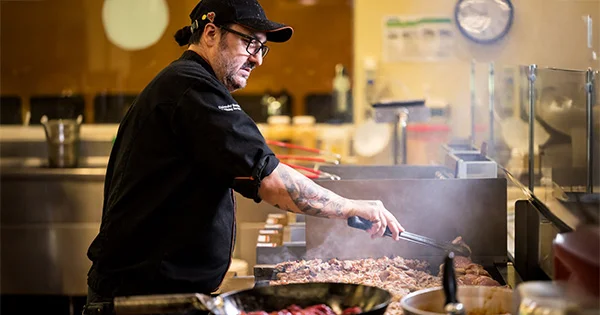 A dining services professional prepares fresh meals for students, illustrating the scale and dedication of campus food resources and nutritional support at Oregon State University.