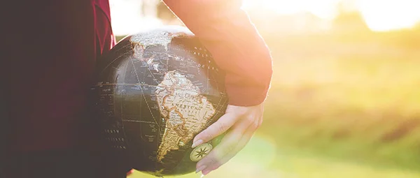 A person holds a globe showing South America, symbolizing a commitment to global health and international community engagement.