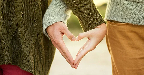 Two people forming a heart with their hands, symbolizing healthy relationships, mutual care, and the importance of sexual and reproductive health resources.