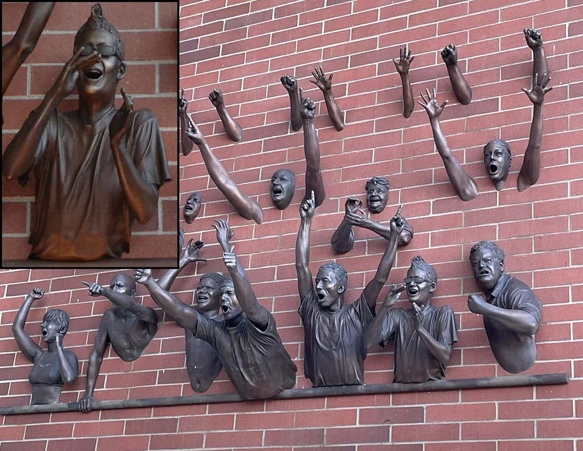 Public art sculpture depicting a crowd of enthusiastic fans. The bronze figures are shown from the waist up or as reaching arms, capturing a high-energy moment of excitement and support at a sporting event.