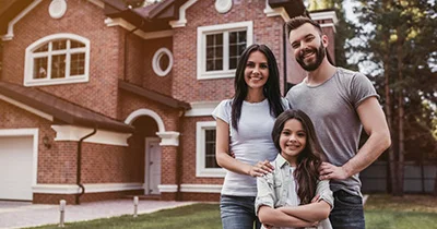 Happy family in front of their new brick home, symbolizing the dream of homeownership.
