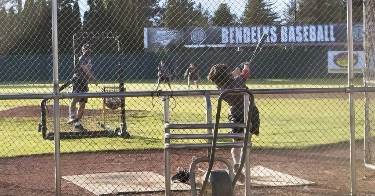 Baseball team practice in batting cages, likely for a high school or youth league.