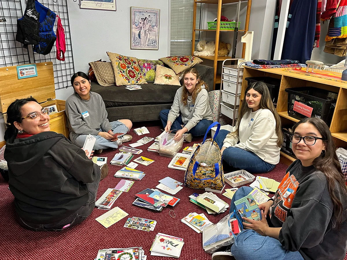 Group of volunteers sorting greeting cards. The cards are spread on the floor around them.