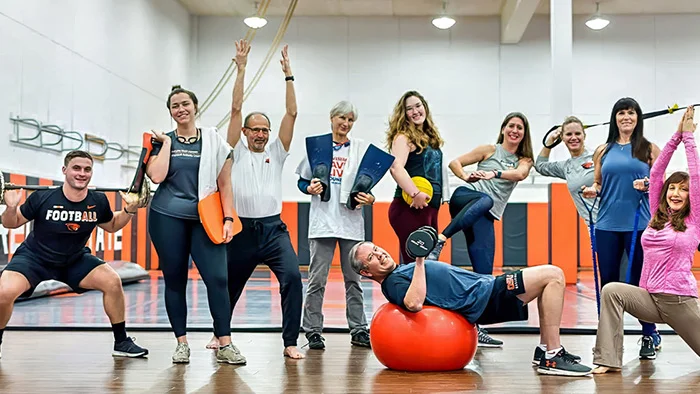 A group of university faculty and staff participating in a fitness program, with smiles and exercise gear.