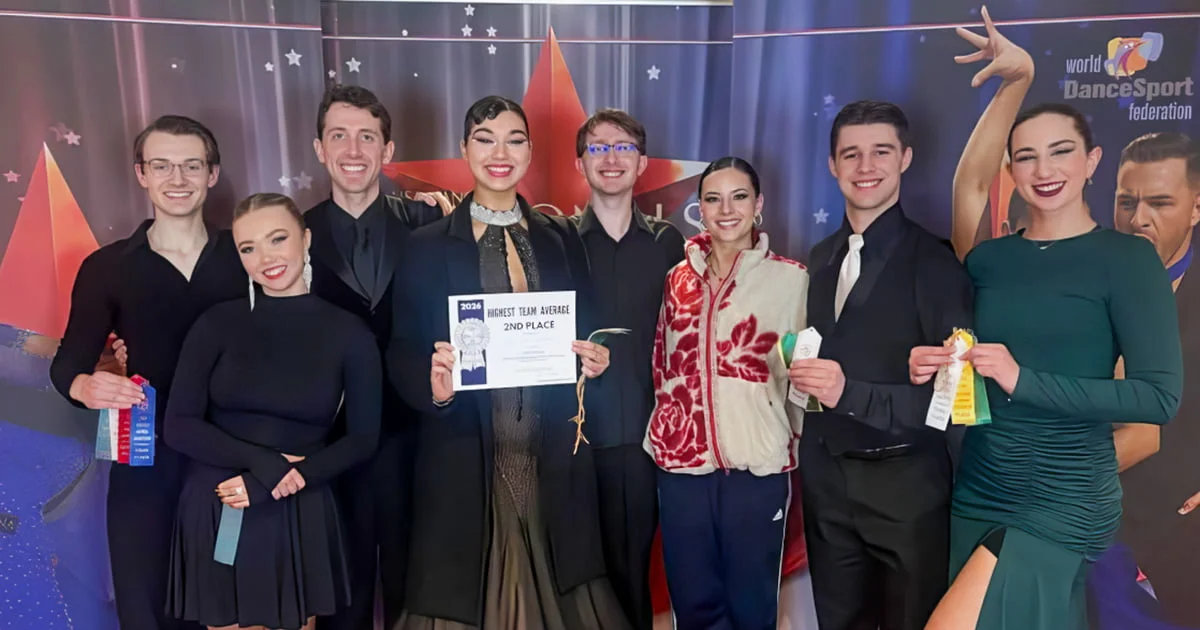 Group of dancers holding ribbons and a 2nd place certificate for highest team average at a ballroom competition.