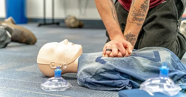 Person practicing life-saving resuscitation skills on a manikin during a hands-on CPR training session.