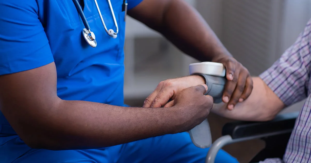 Medical professional monitoring a patient's blood pressure using a wrist cuff during a health check-up.