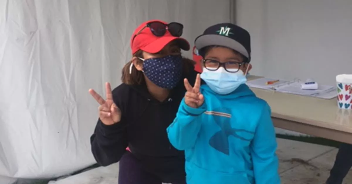 Two people wearing face masks and hats posing for a photo.