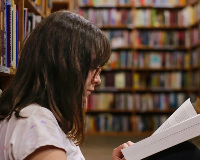 A student reading in a library, symbolizing academic pursuit or study.
