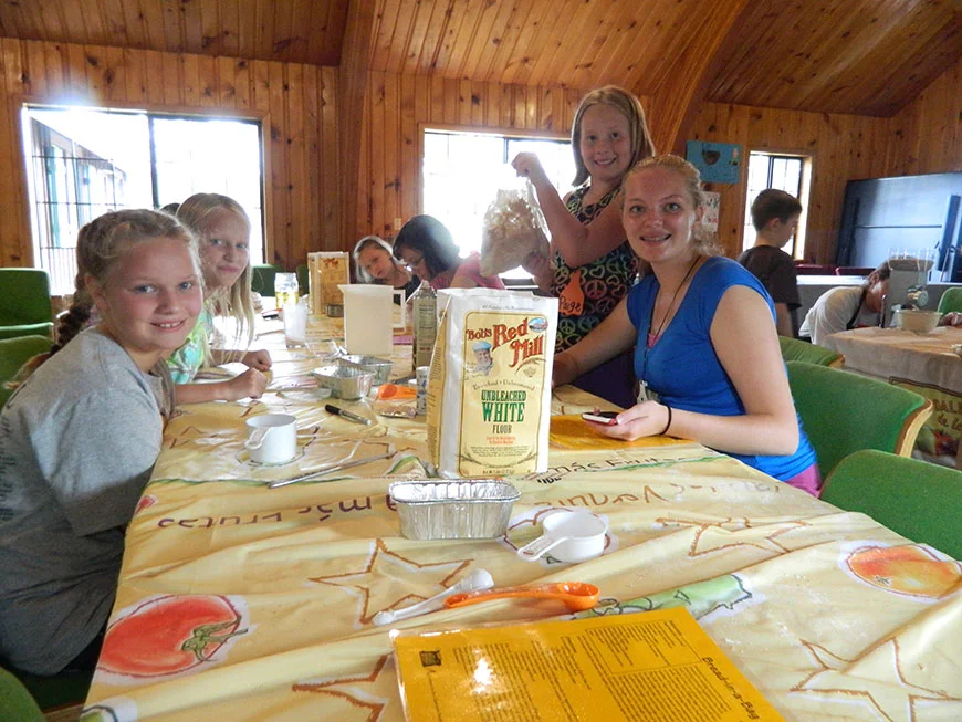 A group of young girls sitting at a table with craft supplies.