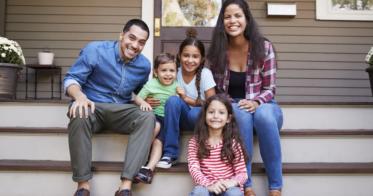 Family sitting on front porch of home