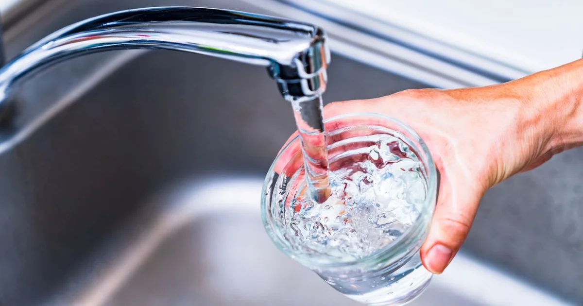 hand holding glass that is filling with water from faucet