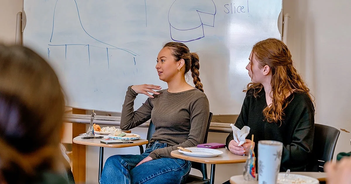 Students engaged in a classroom discussion, illustrating an interactive and collaborative learning environment.