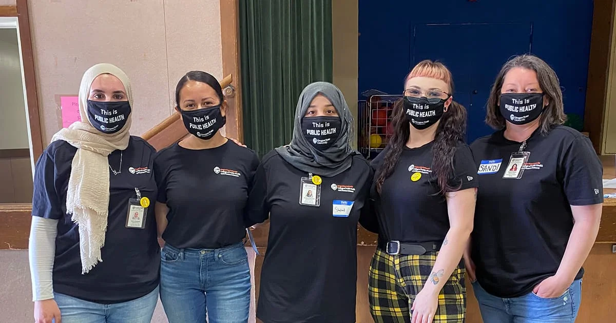 Five public health students or professionals in uniform t-shirts and masks, representing a community health team or academic program.