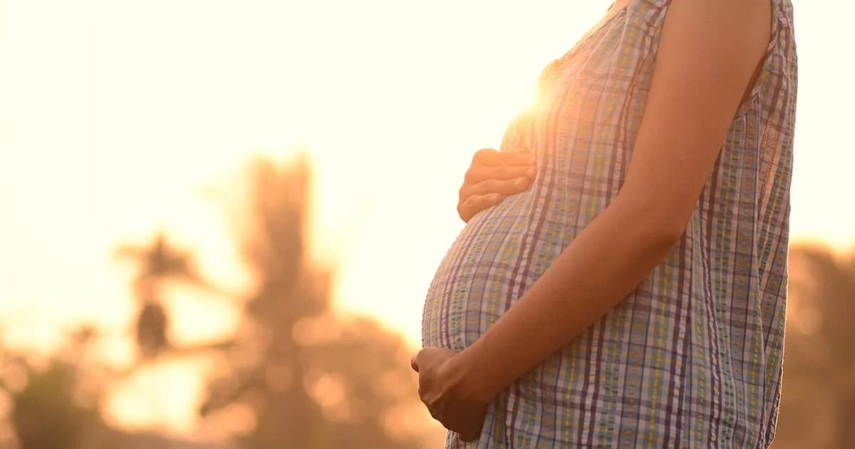 Profile of a pregnant woman at sunset, symbolizing maternal health, prenatal care, or the journey of parenthood.
