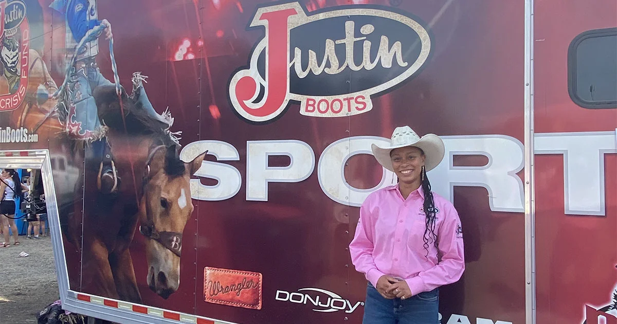 Alyssa Woodberry stands in front of a Justin Boots Sport trailer while completing an athletic training internship with the Justin Sportsmedicine Team.