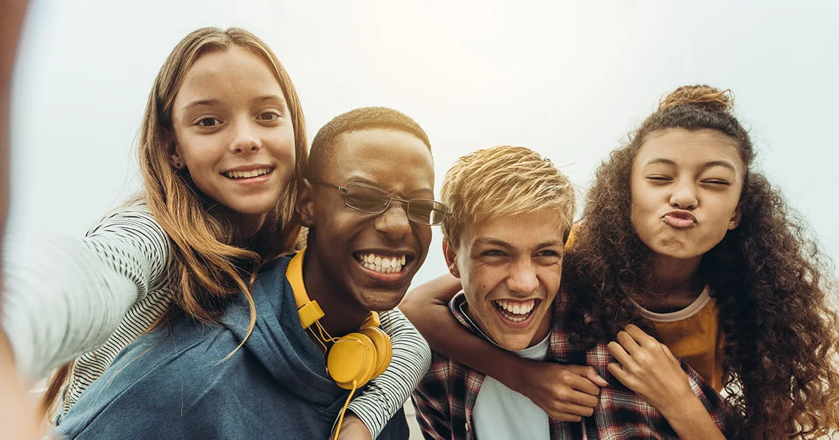 Diverse group of friends sharing a joyful moment and piggybacking outdoors to illustrate youth friendship and social connection.