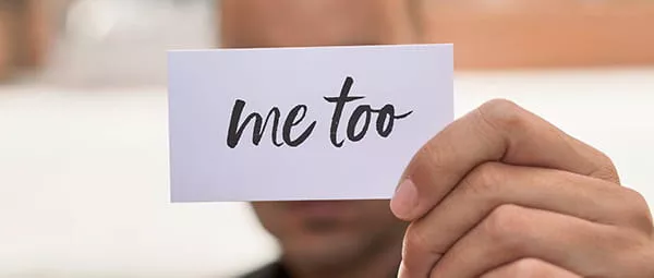 hand holding a card with "me too" written on it