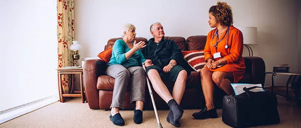 health care worker making home visit to elderly couple